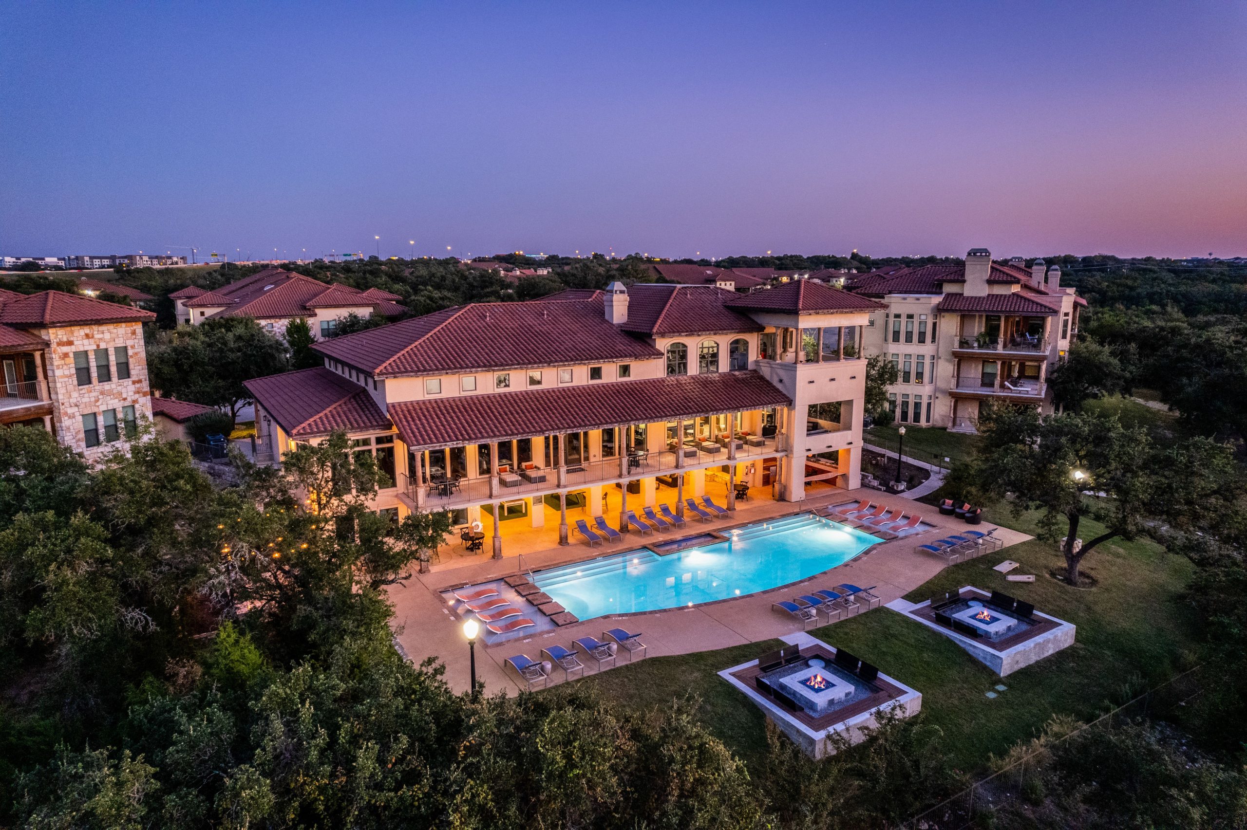 stunning drone view of a multi-family property and its amenities at twilight