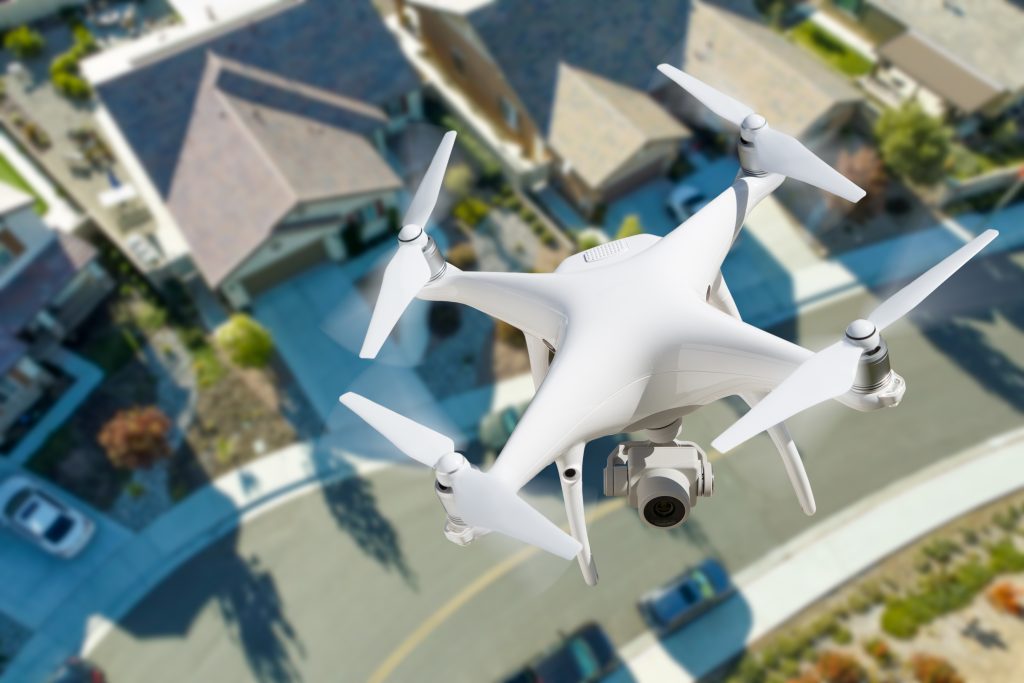 white drone flying over houses to help illustrate drone photography rules in residential real estate
