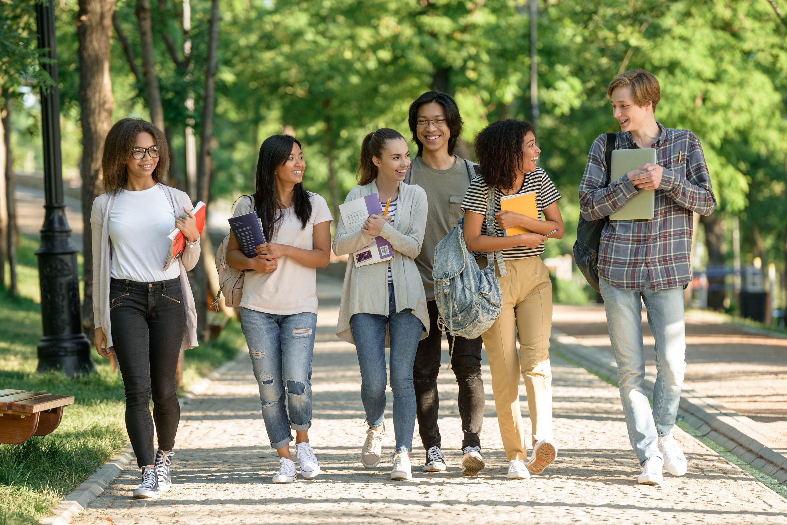 group of students walking together on a tree lined path looking for a student lease
