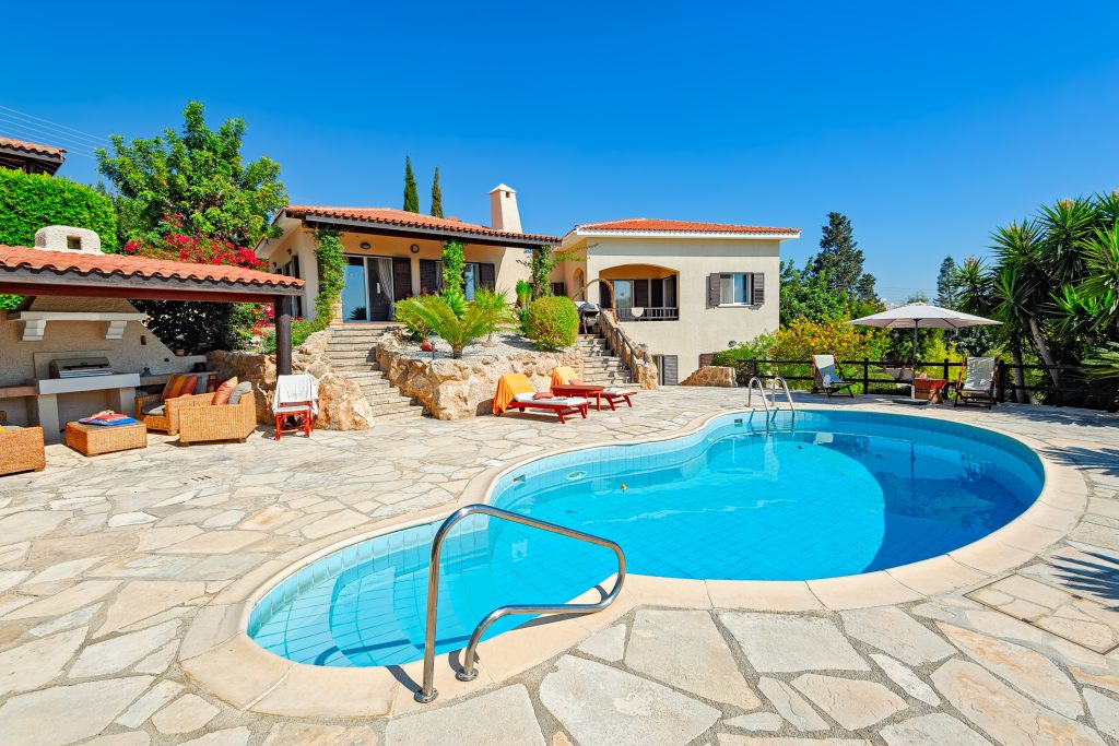 image of a clean and clear pool with a tuscan style home in the background to illustrate how to get your pool ready for summer