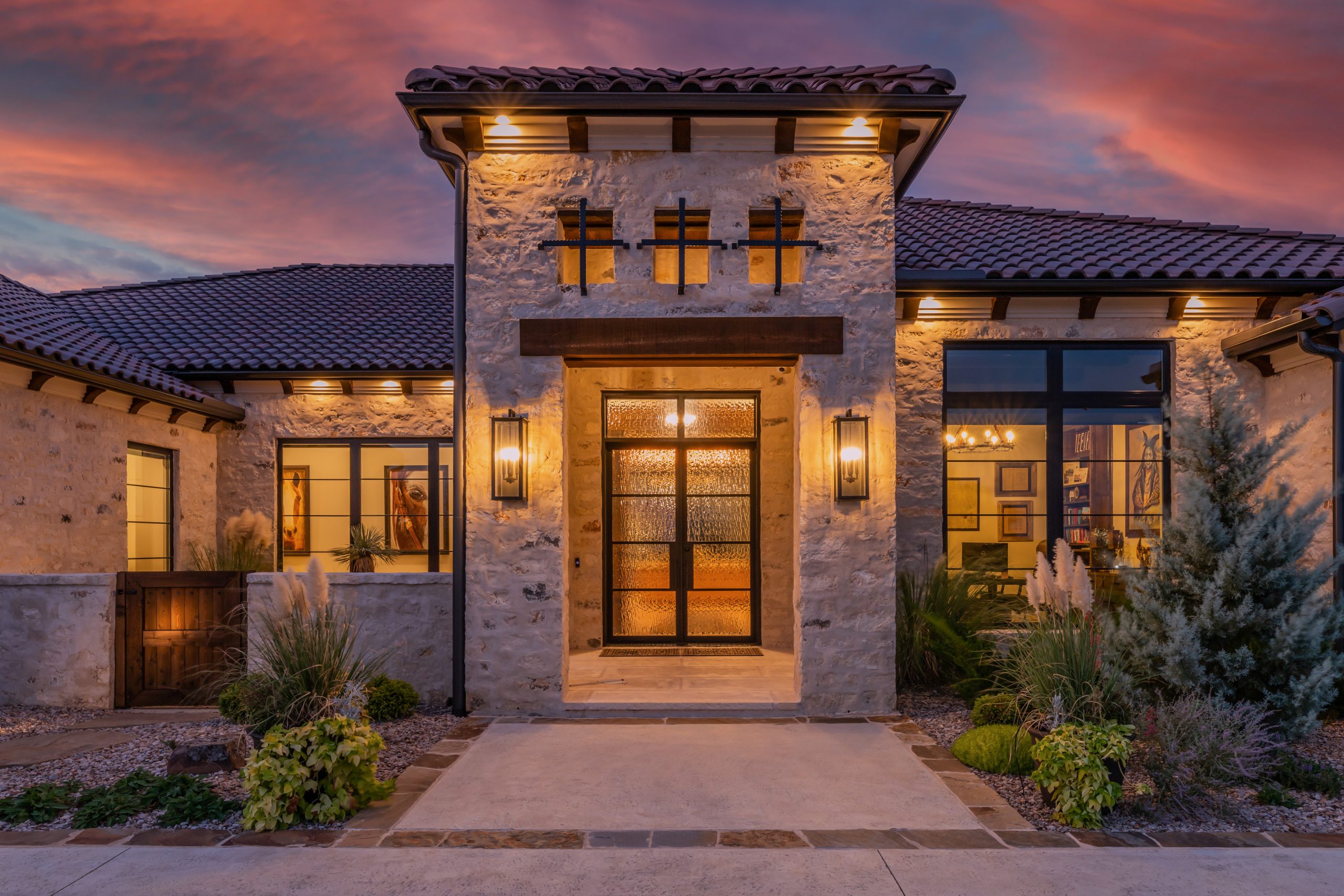 twilight image of a stone residential home lit up with a warm glow