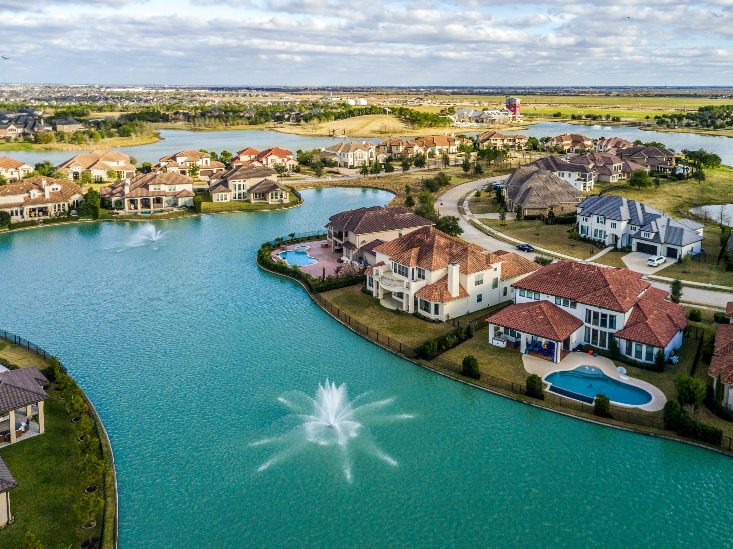 drone view of a residential neighborhood with a large pond and waterfront properties